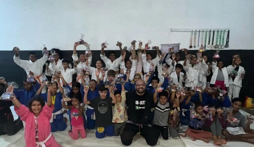 Crianças e professor reunidos no tatame depois da entrega dos presentes